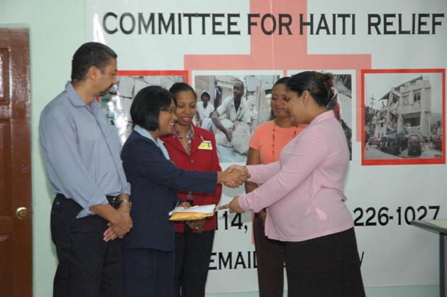 Minister of Human Services and Social Security and Chairperson of the National Committee for Haiti Relief, Priya Manickchand receives donation from a Representative of Courts at the Civil Defence Commission office, Thomas Lands.