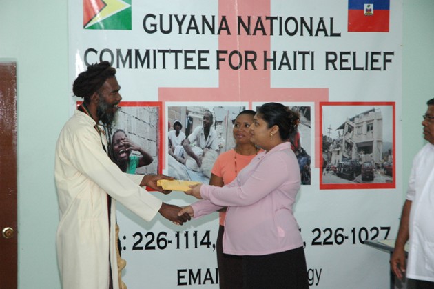 Minister Manickchand receives donation from a Representative of the Guyana Rastafarian Community and Council.