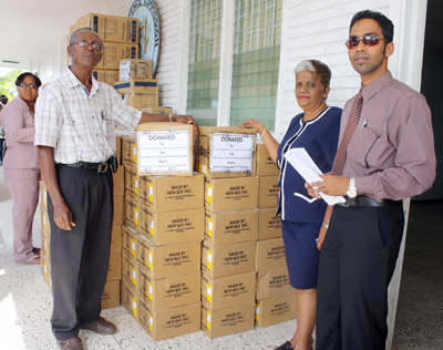 New GPC Inc. Marketing Manager, Trevor Bassoo, HR Manager, S. Vieira  and Production Consultant, Donald Cox  stand beside the boxes of pharmaceuticals and medical supplies donated by thier company